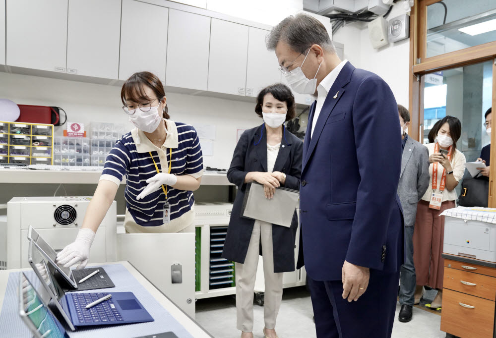 문재인 대통령이 18일 오전 한국판 뉴딜의 일환으로 그린 스마트 교육을 시행 중인 서울 중구 창덕여자중학교를 방문해 테크매니저로부터 스마트 교육에 활용하는 태블릿PC에 대한 설명을 듣고 있다. 연합뉴스