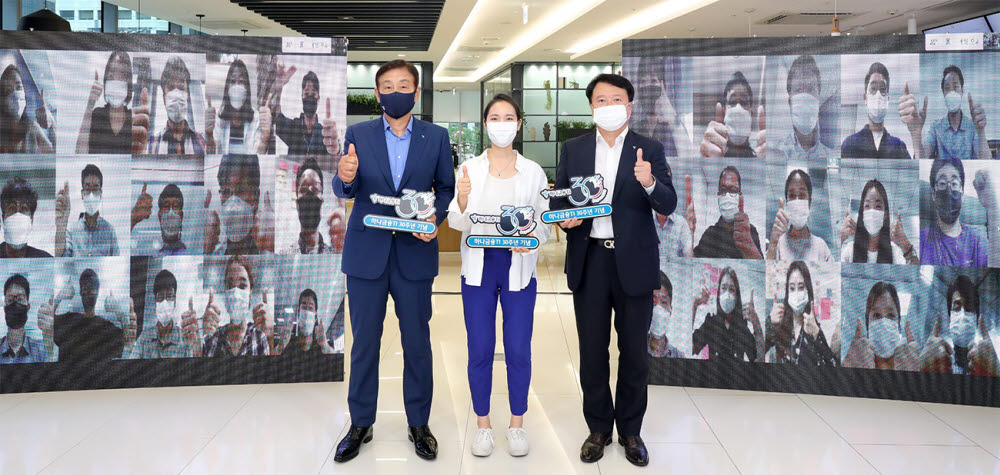 김정태 하나금융그룹 회장(왼쪽), 유시완 하나금융티아이 사장(오른쪽), 하나금융티아이 직원 대표가 1일 대형 스크린이 마련된 을지로 하나은행 본점에서 화상 대화에 참여한 직원들과 함께 최고가 되자는 의미로 엄지 손가락을 치켜 들며 기념촬영을 하고 있다.