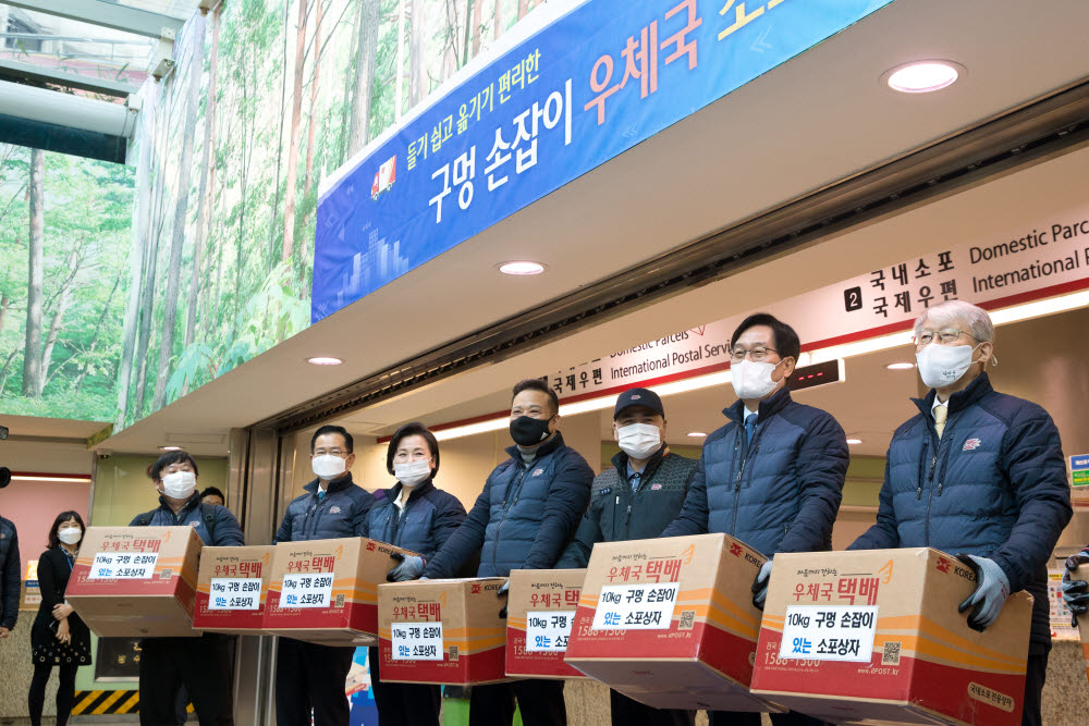 오른쪽부터 최기영 과학기술정보통신부 장관, 신동근 더불어민주당 의원, 이일곤 집배원, 이동호 우정노조위원장, 이수진 민주당 의원, 이용빈 민주당 의원, 안진걸 민생경제연구소장이 23일 서울중앙우체국에서 우체국 구멍손잡이 소포상자를 들어보이고 있다.