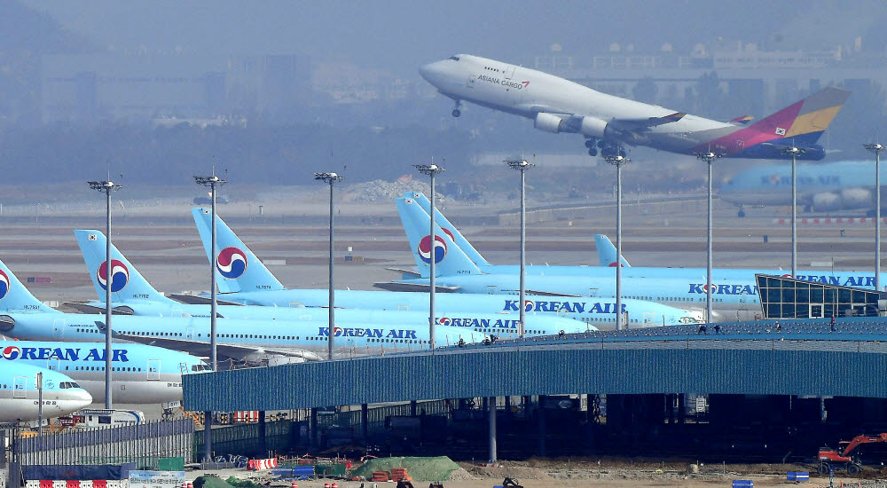 인천국제공항 주기장에 서 있는 대한항공 항공기 뒤로 아시아나항공 화물기가 이륙하고 있다. 인천=이동근기자 foto@etnews.com