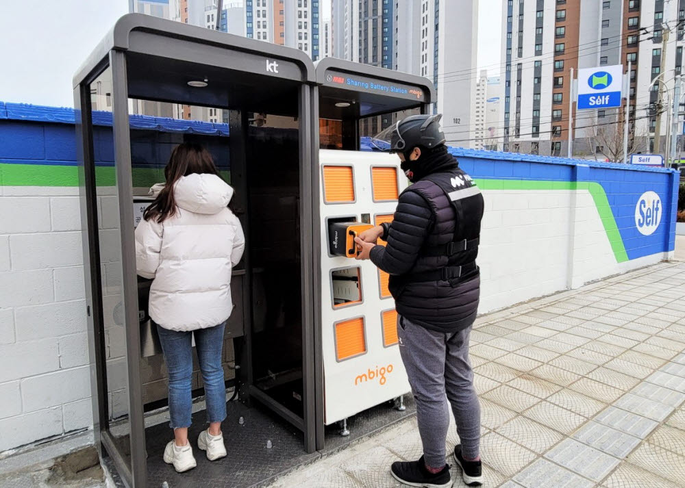 지난 7일 부산 부경대 인근 공중전화 부스에 설치된 전기오토바이 배터리 교환 시설을 한 배달라이더가 이용하고 있다.