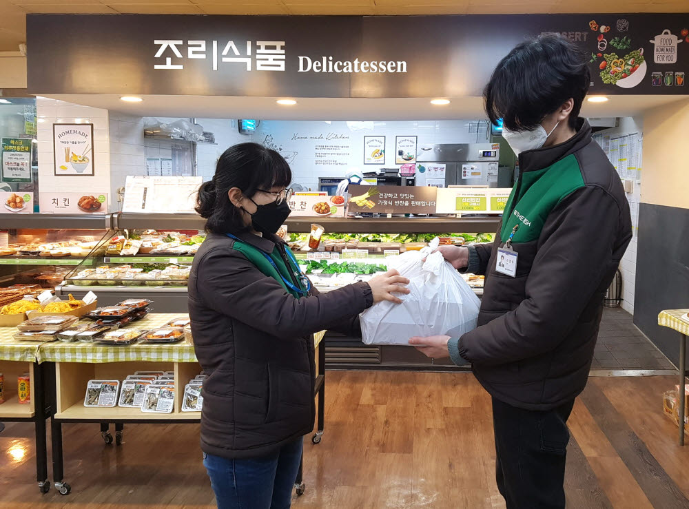 GS수퍼마켓 직원이 주문 들어온 상품을 배송직원에게 전달하고 있다.