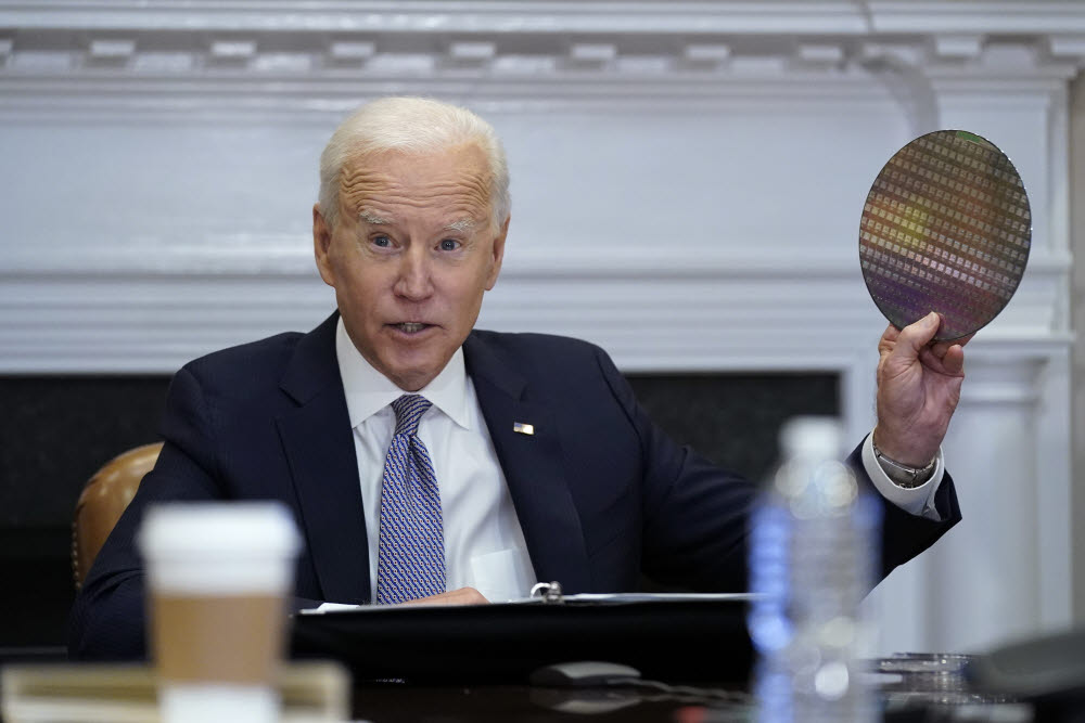 조 바이든 미국 대통령이 12일(현지시간) 미국 백악관에서 반도체 영상회의에 참석하며 웨이퍼를 들어올리고 있다.