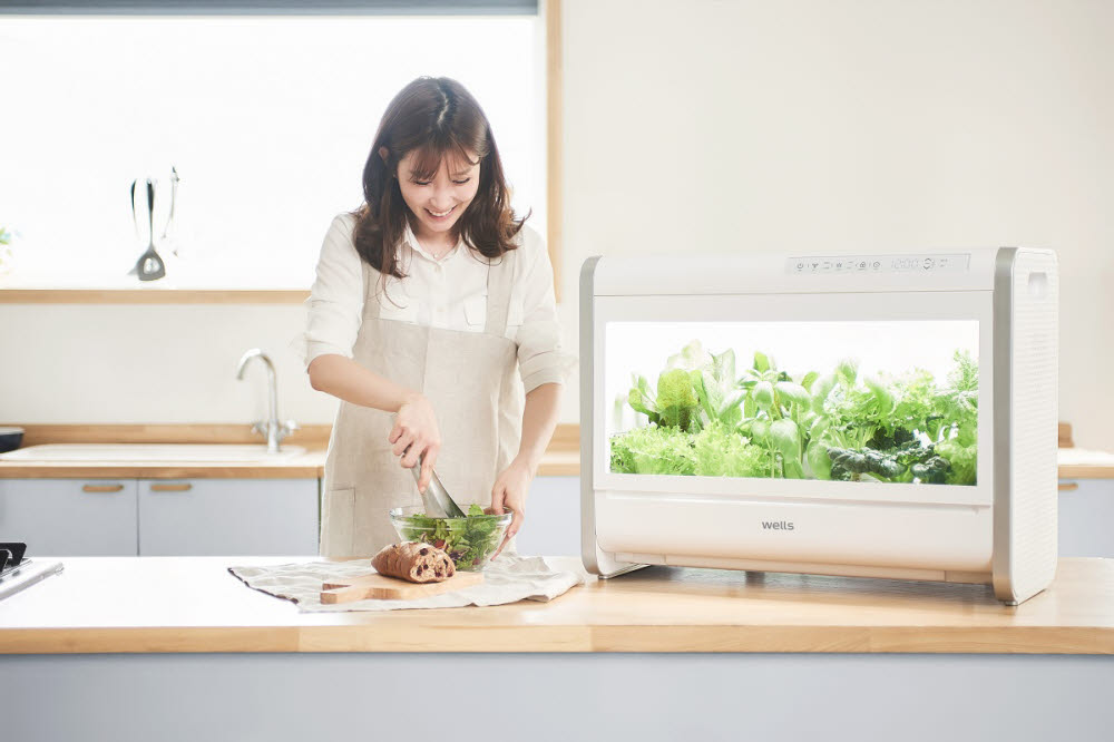 모델이 가정용 식물재배기 웰스팜으로 재배된 기능성 채소를 이용해 요리를 하고 있다.