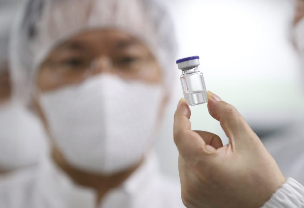코로나19 백신을 생산하는 경북 안동 SK바이오사이언스 공장에서 관계자들이 임상 3상 개발 중인 새로운 코로나19 백신을 들어 보이고 있다. 연합뉴스