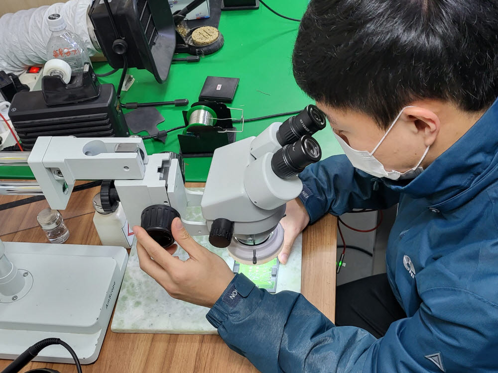 연구원이 개발한 통신칩을 살펴보고 있다