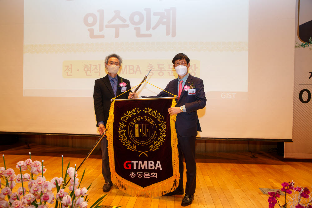 이용범 제5대 GTMBA 총동문회장(오른쪽)이 정기섭 제4대 회장으로부터 GTMBA 깃발을 인계받고 있다.