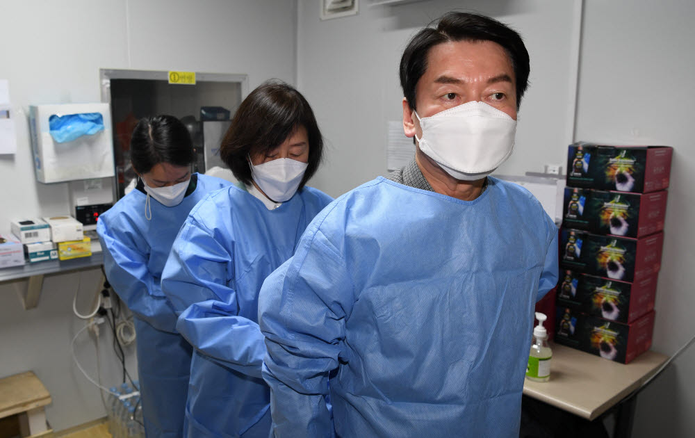 안철수 국민의당 대선후보가 설 연휴 마지막 날인 2일 서울 중구보건소 선별진료소를 찾아 부인 김미경 교수, 딸 안설희 박사와 함께 코로나19 검체 채취 봉사활동을 하기에 앞서 가운을 착용하고 있다. 국회사진기자단.