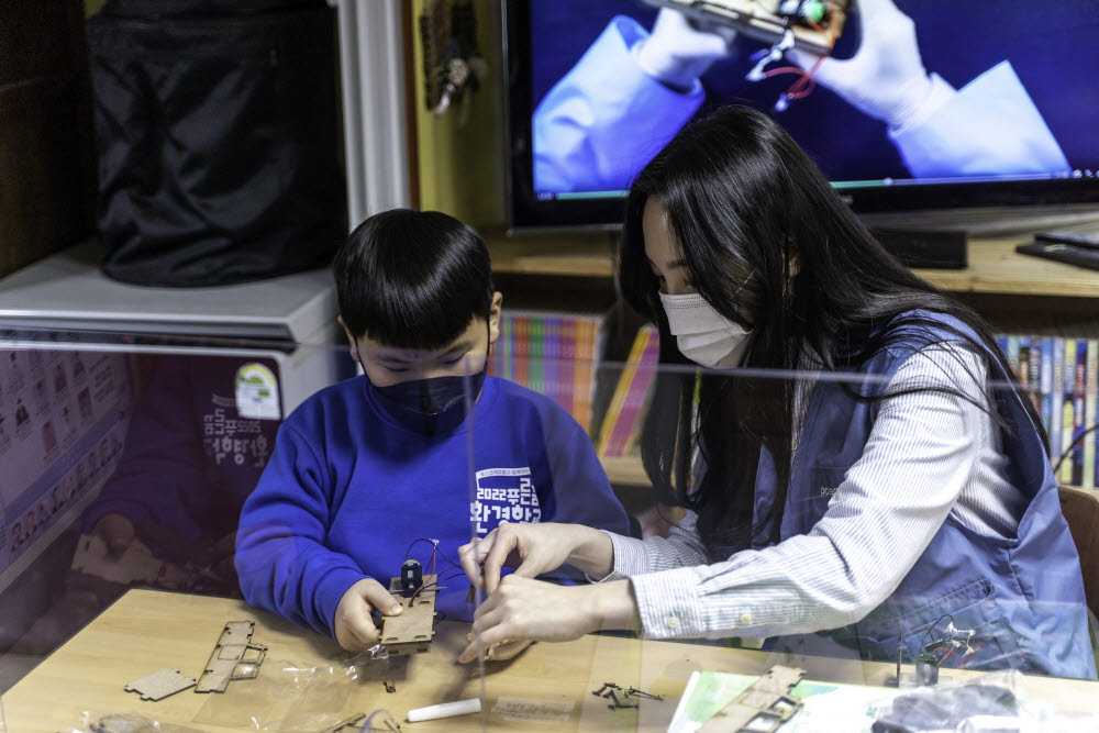 포스코케미칼 직원이 포항 지역아동센터에서 진행한 푸른꿈 환경학교에서 전기차 모형을 함께 조립하고 있다.