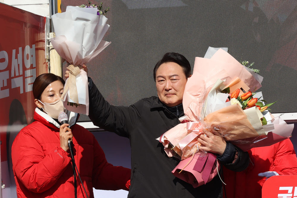 윤석열 국민의힘 대선후보가 17일 경기도 용인 수지구 테이스티 애비뉴 옆 공터에서 열린 역동적 혁신성장 대한민국 만들기 유세에서 꽃다발을 들어 보이고 있다.국회사진기자단.