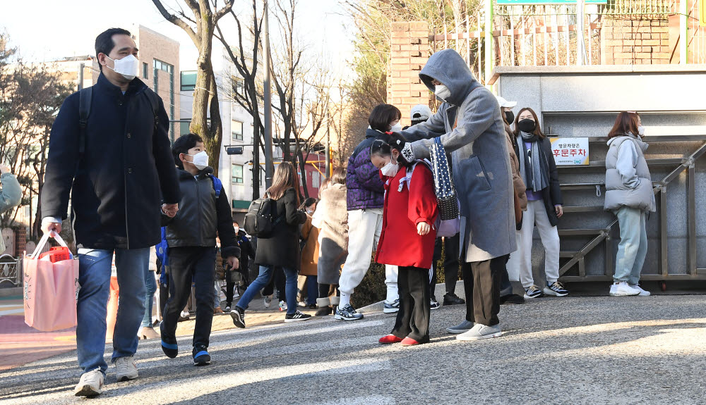 2022학년도 새학기 첫 날인 2일 서울 노원구 태랑초등학교에서 한 학부형이 등교하는 자녀의 가방을 메어주고 있다.