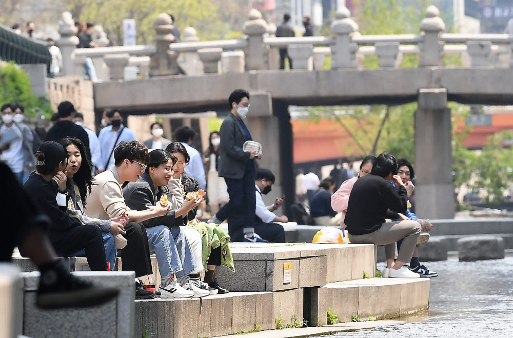 사회적 거리두기 조치가 모두 해제된 18일 서울 청계천에서 직장인들이 점심 식사를 하며 휴식을 취하고 있다.