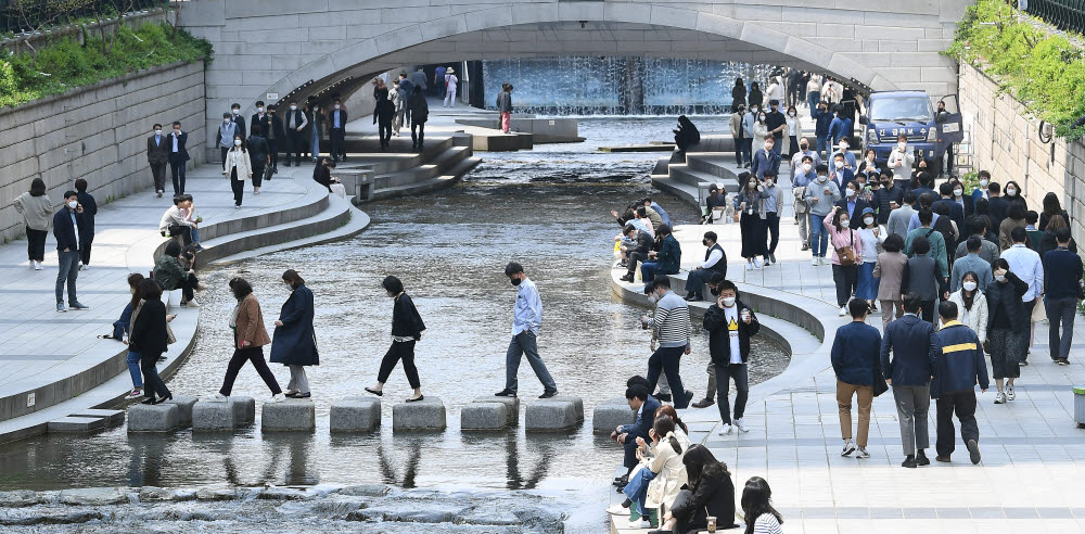 사회적 거리두기 조치가 모두 해제된 18일 서울 청계천에서 직장인들이 점심시간 여유를 즐기며 셀피를 찍고 있다. 이동근기자 foto@etnews.com