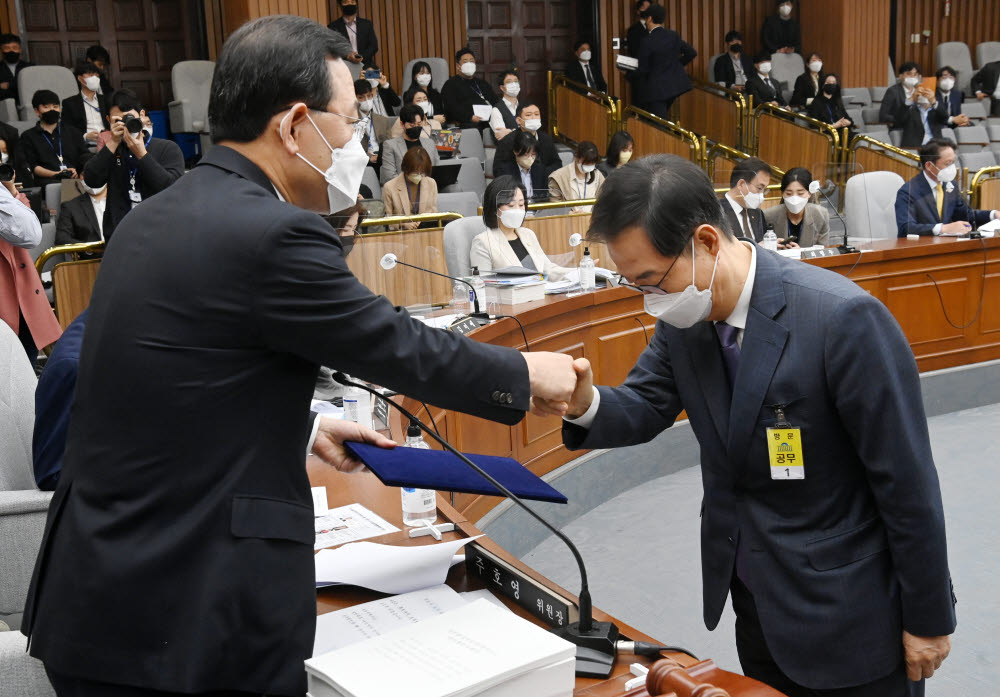 한덕수 국무총리 후보자가 2일 국회에서 열린 인사청문회에서 주호영 위원장에게 선서문을 제출한 뒤 악수하고 있다.