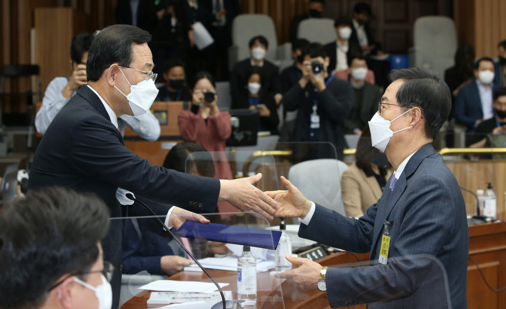 한덕수 국무총리 후보자(오른쪽)가 주호영 위원장에게 선서문을 전달하며 악수하고 있다. <공동취재>