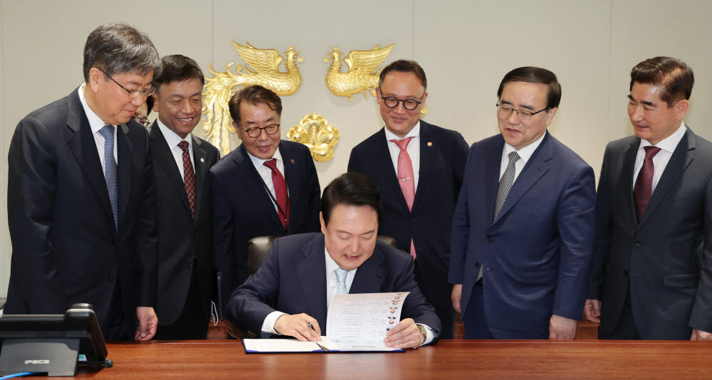 윤석열 대통령이 10일 서울 용산에 새로 마련된 대통령 집무실에서 1호 법안에 서명하고 있다. 뒷줄 왼쪽부터 김대기 비서실장, 강인선 대변인, 최상목 경제수석, 최영범 홍보수석, 안상훈 사회수석, 김성한 국가안보실장, 김용현 대통령경호처장. 연합뉴스