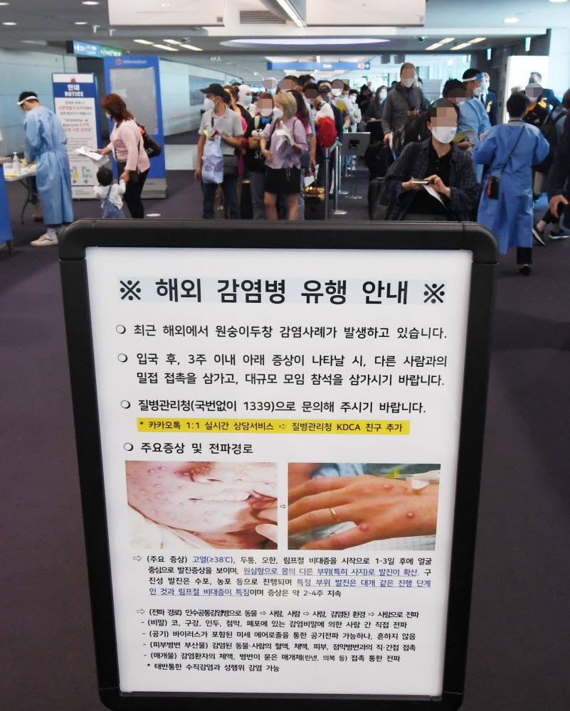 27일 오전 인천국제공항 제1터미널 입국장에 해외입국자들이 검역을 받기 위해 대기하고 있다. 승객들 앞에는 원숭이두창 관련 안내문이 세워져 있다. 연합뉴스