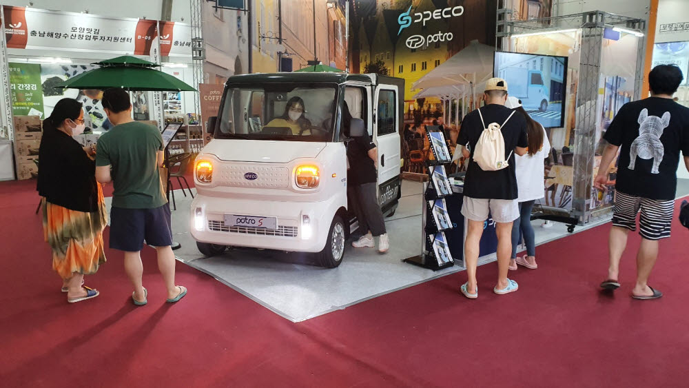 관람객들이 보령머드축제 해양 머드·신산업관에 마련된 디피코 전시부스에서 전기화물차를 살펴보고 있다.