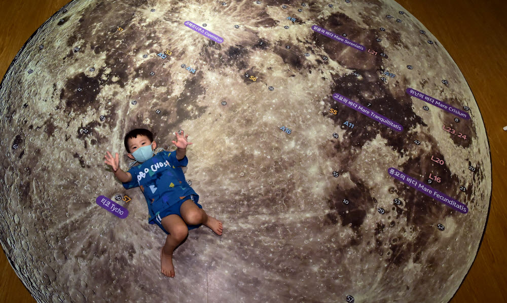 한 어린이가 달에 누워보고 있다.