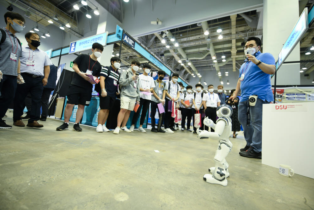 K-ICT 위크인부산 2021에서 관람객들이 뇌파로 움직이는 로봇을 구경하고 있다.
