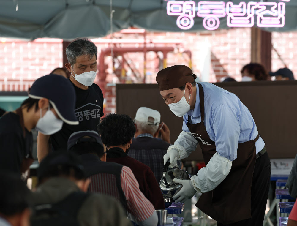 윤석열 대통령이 추석 연휴 첫날인 9일 서울 중구 명동성당 내 무료급식소인 명동밥집에서 한 시민에게 물을 따라주고 있다. 대통령실 제공