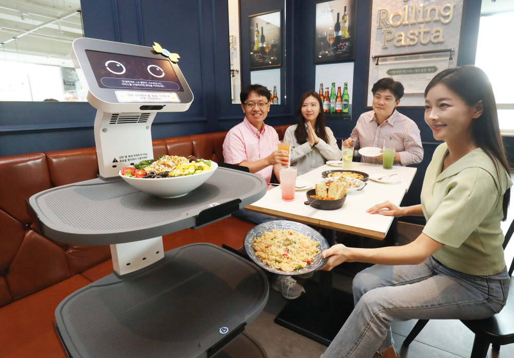 한 매장에서 LG 클로이 서브봇이 손님에게 음식을 서빙하고 있다.