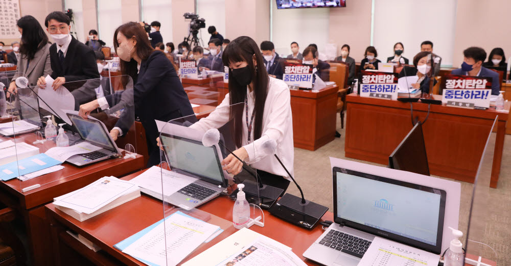 4일 국회에서 열린 법제사법위원회 국정감사에서 더불어민주당 측이 정치탄압 중단하라 피켓을 의원석 노트북에 붙이자 국민의힘 관계자들이 민생국감을 촉구하는 피켓을 의원석 노트북에 붙이고 있다. 연합뉴스.