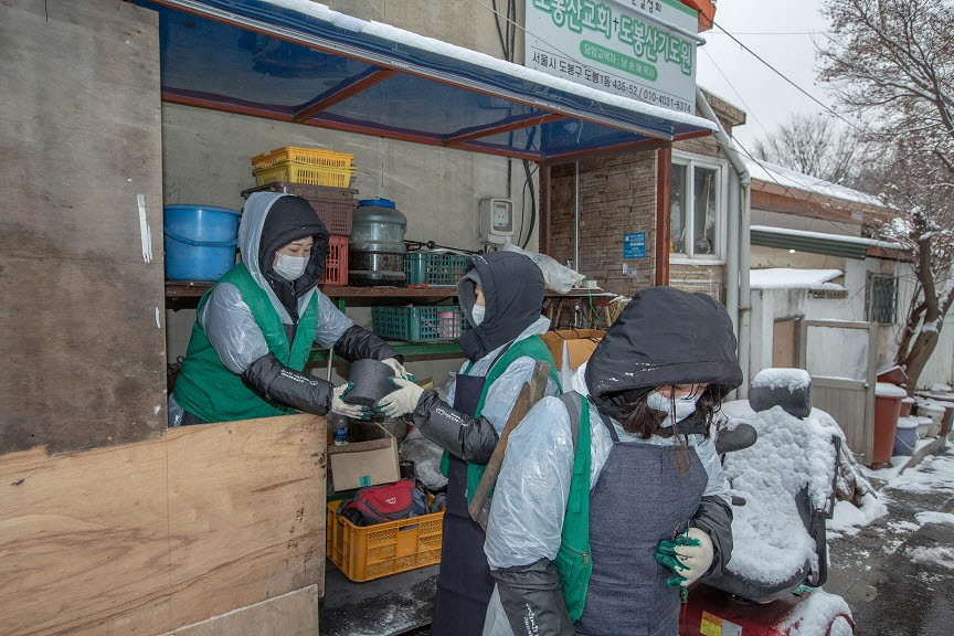 리치앤코 직원들이 서울 도봉구에서 주민들에게 연탄 배달을 하고 있다.